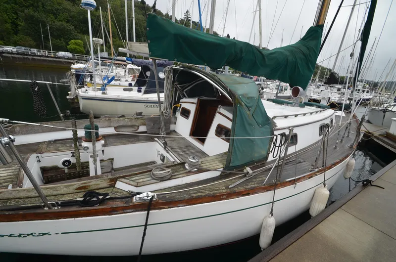 Slide: The Image of 1978 Cheoy Lee Offshore 32 sailboat docked in a marina, featuring green sail covers. - 3