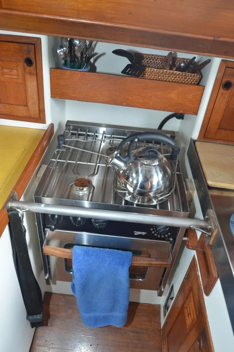 Slide: The Image of 1978 Cheoy Lee Offshore 32 yacht kitchen with stove, kettle, and wooden cabinetry. - 37