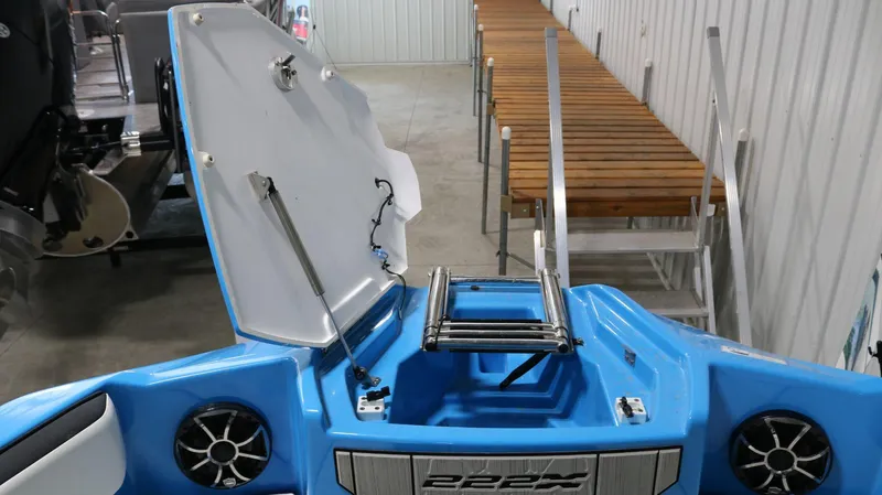 Slide: The Image of 2023 Yamaha Boats 222XD with open storage compartment and ladder in a garage setting. - 6