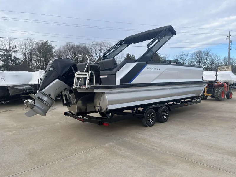 Slide: The Image of 2023 Manitou Explore 24 Switchback pontoon boat on trailer, outdoor setting. - 3