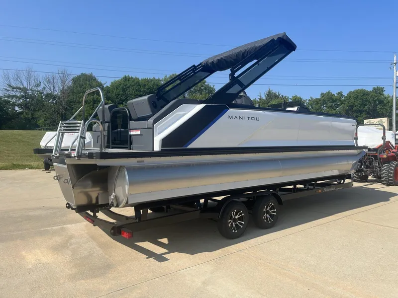 Slide: The Image of 2023 Manitou Explore 24 Switchback pontoon boat on trailer, parked outdoors. - 4