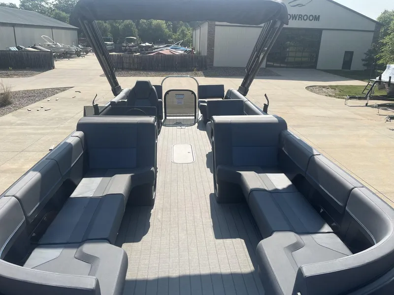 Slide: The Image of 2023 Manitou Explore 24 Switchback pontoon boat with spacious seating in a showroom. - 7