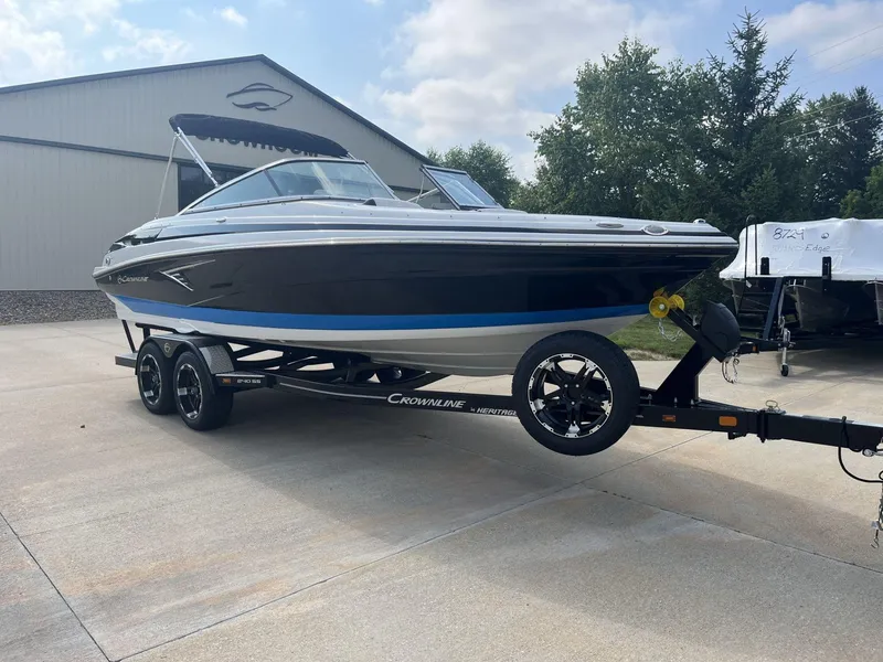 Slide: The Image of 2024 Crownline 240SS boat on trailer, parked outdoors near a building. - 4