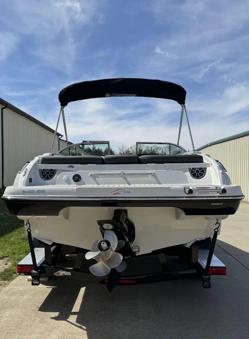 Slide: The Image of 2024 Crownline 240SS boat with canopy, rear view, parked on trailer under blue sky. - 6