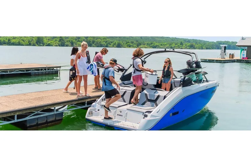 Slide: The Image of 2024 Yamaha Boats 222XE at dock with people boarding, scenic lake background. - 13