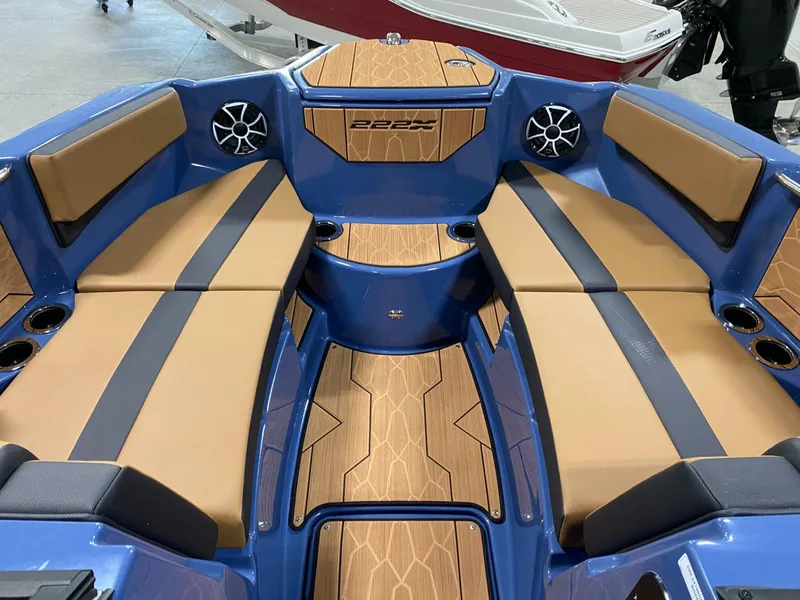 Slide: The Image of 2024 Yamaha Boats 222XE interior with blue and tan seating, wood accents, and speakers. - 4