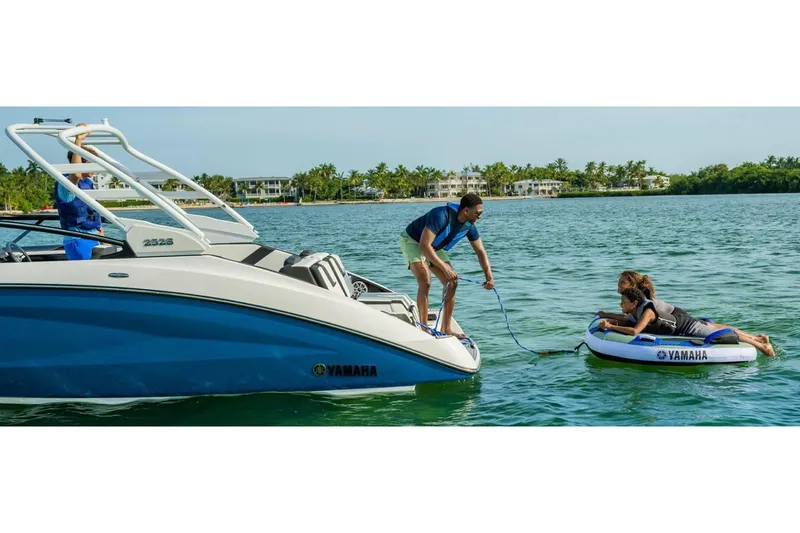 Slide: The Image of 2024 Yamaha Boats 252S towing inflatable raft on scenic water. - 15