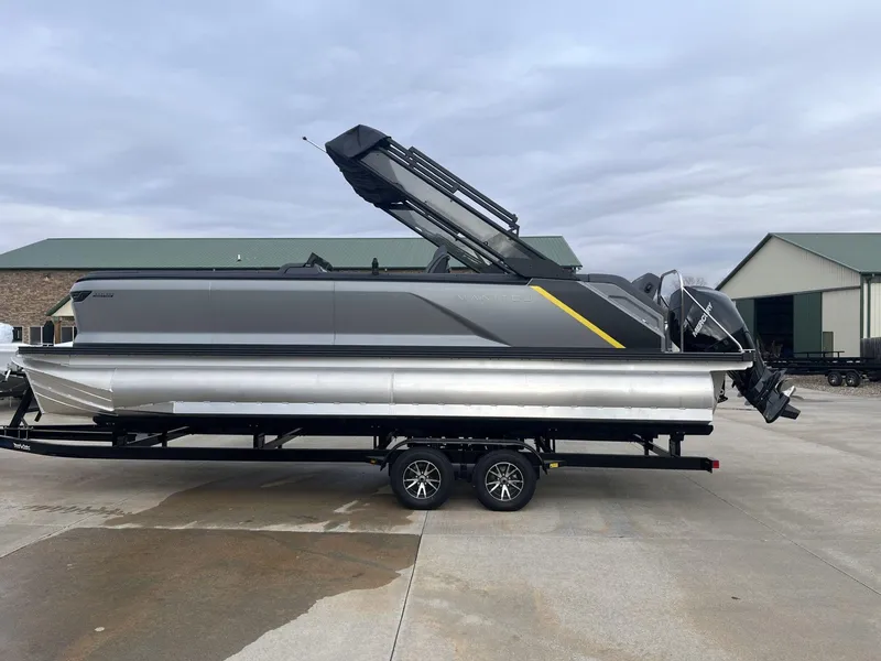 Slide: The Image of 2024 Manitou Explore 24 Navigator pontoon boat on trailer, outdoor setting. - 1