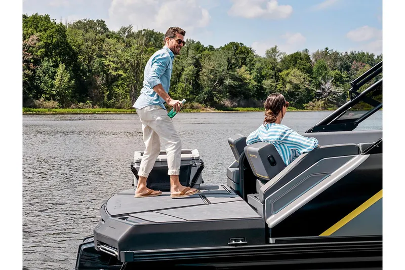 Slide: The Image of 2024 Manitou Explore 24 Navigator on a scenic lake with two people enjoying the view. - 15