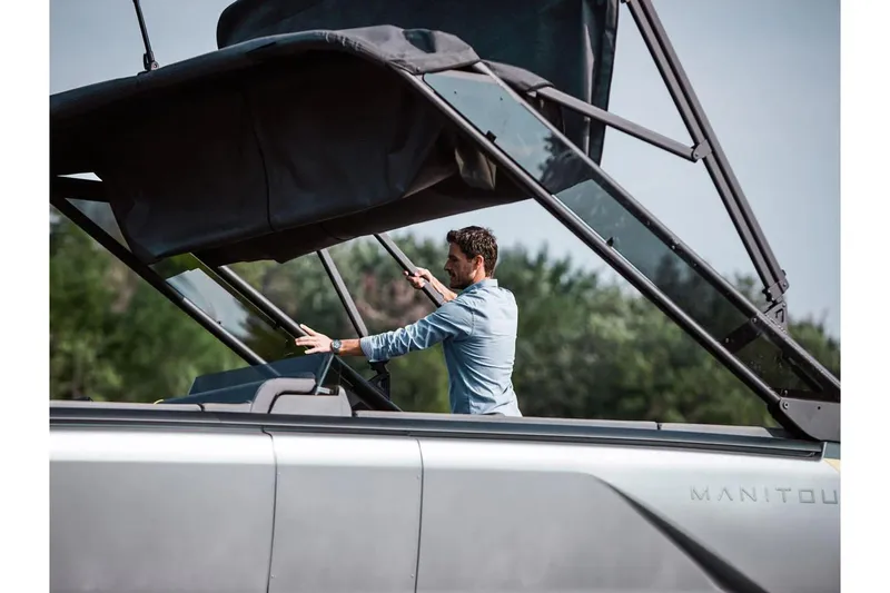 Slide: The Image of Man adjusting canopy on 2024 Manitou Explore 24 Navigator boat. - 20