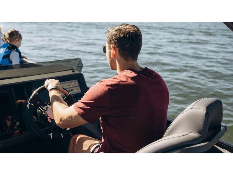 Slide: The Image of Man driving 2024 Manitou Explore 24 Navigator boat on a sunny day. - 22