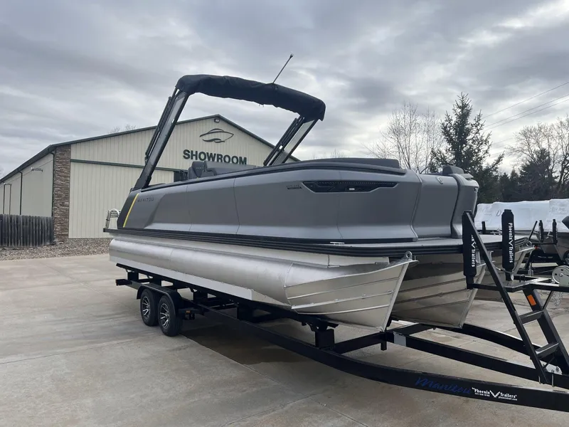 Slide: The Image of 2024 Manitou Explore 24 Navigator pontoon boat on trailer outside showroom. - 4