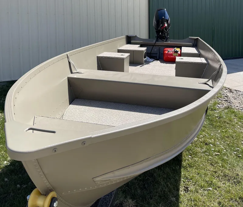Slide: The Image of 2024 Alumacraft V-16 Tiller boat with outboard motor, parked on grass. - 11