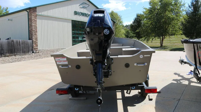 Slide: The Image of 2024 Alumacraft V-16 Tiller boat with outboard motor, parked outside a showroom. - 4