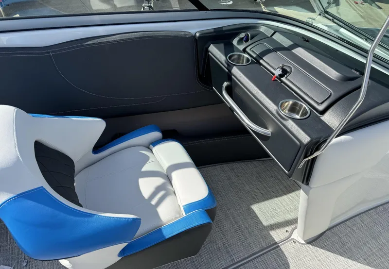 Slide: The Image of 2024 Crownline 220SS boat interior with blue and white seating, dashboard, and cup holders. - 11