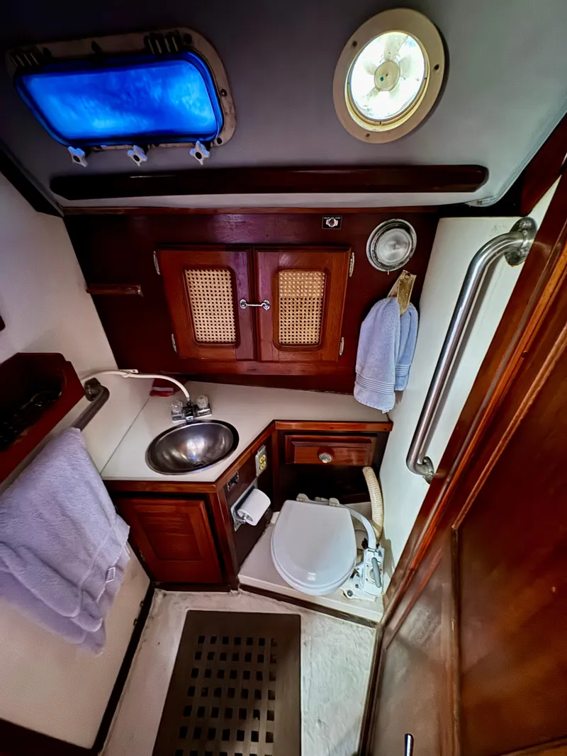 Slide: The Image of 1979 Islander IP Peterson 40 yacht bathroom with sink, toilet, and wooden cabinetry. - 11