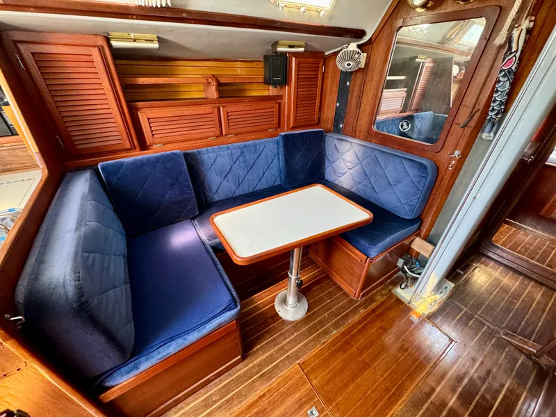 Slide: The Image of Interior of 1979 Islander IP Peterson 40 sailboat with blue cushioned seating and wooden table. - 16
