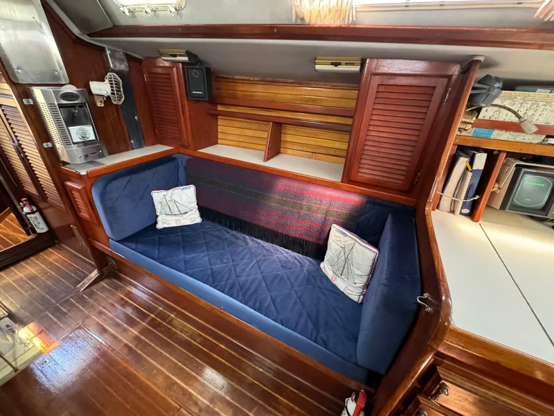 Slide: The Image of 1979 Islander IP Peterson 40 yacht interior with blue cushioned seating and wooden cabinetry. - 21