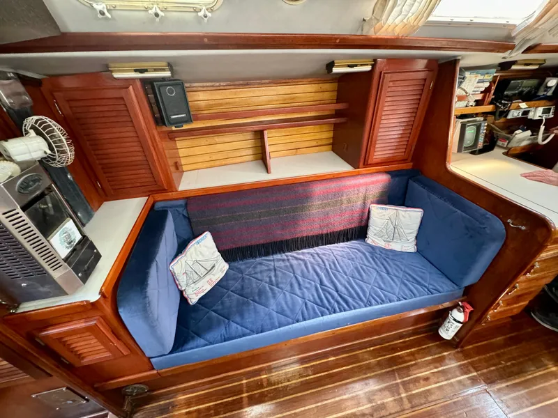 Slide: The Image of Interior of 1979 Islander IP Peterson 40 sailboat with blue cushioned seating and wooden cabinetry. - 24