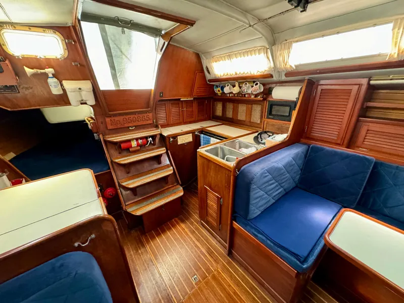 Slide: The Image of Interior of 1979 Islander IP Peterson 40 sailboat with wooden finish and blue seating. - 25