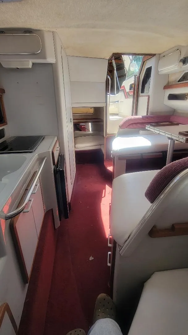 Slide: The Image of Interior of a 1990 Sea Ray 270 Sundancer boat with red carpet and compact kitchen. - 7