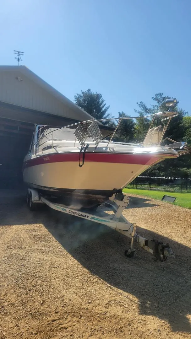 Slide: The Image of 1990 Sea Ray 270 Sundancer boat on trailer, partially inside a garage, sunny day. - 8