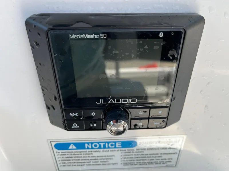Slide: The Image of JL Audio MediaMaster 50 on 2022 Aquasport 2300 Center Console, wet surface, notice label visible. - 12