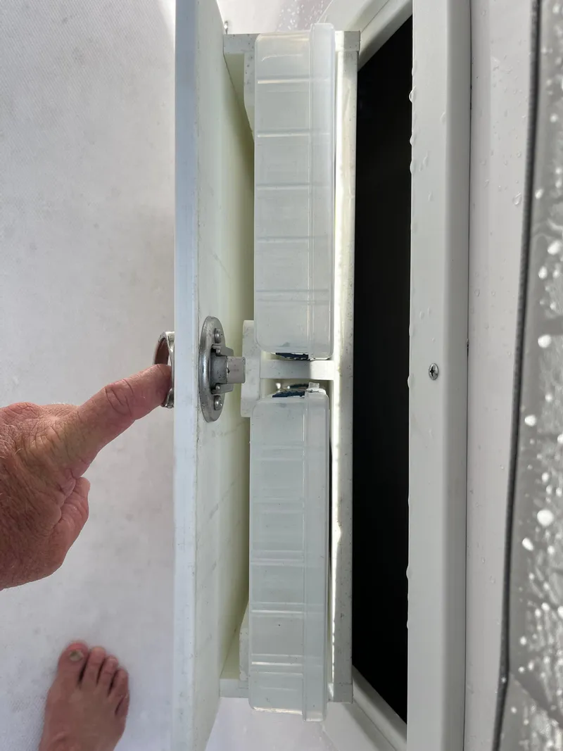 Slide: The Image of 2022 Aquasport 2300 Center Console boat compartment with latch mechanism. - 8