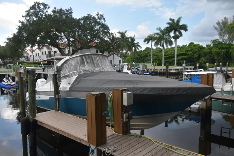 Slide: The Image of 2018 Pronautica 34 boat docked, covered, with palm trees and houses in the background. - 3