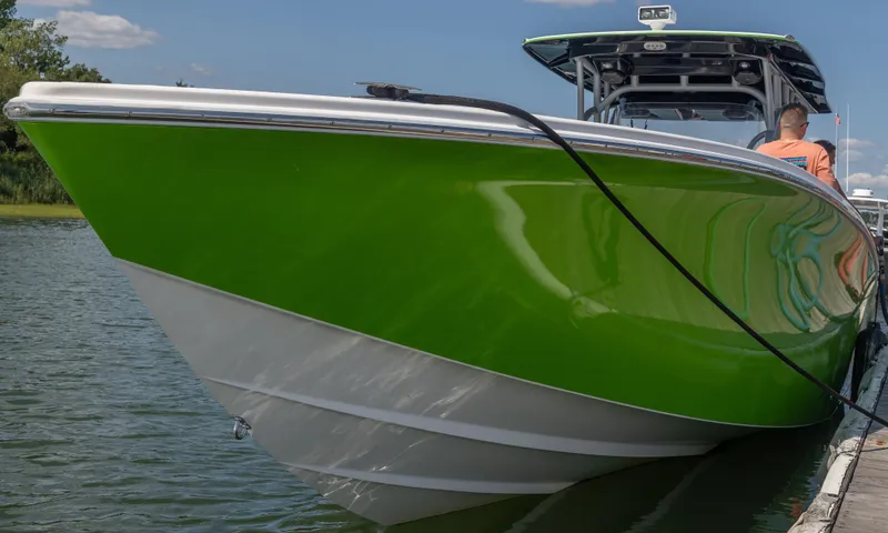 Slide: The Image of 2014 Nor-Tech 390 Sport Cuddy Center Console in vibrant green docked on calm water. - 2