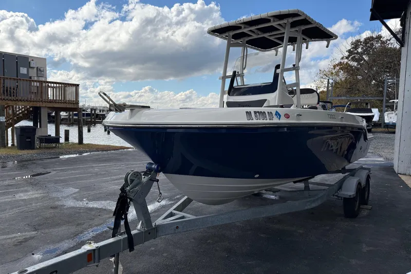 Slide: The Image of 2023 Bayliner Trophy T20CC boat on trailer, parked near waterfront under cloudy sky. - 5