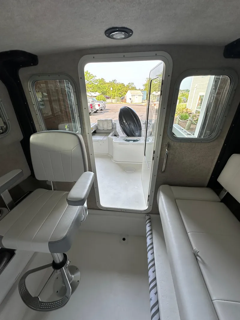 Slide: The Image of Interior of 2025 Parker 2120 Sport Cabin boat with white seating and open door. - 13