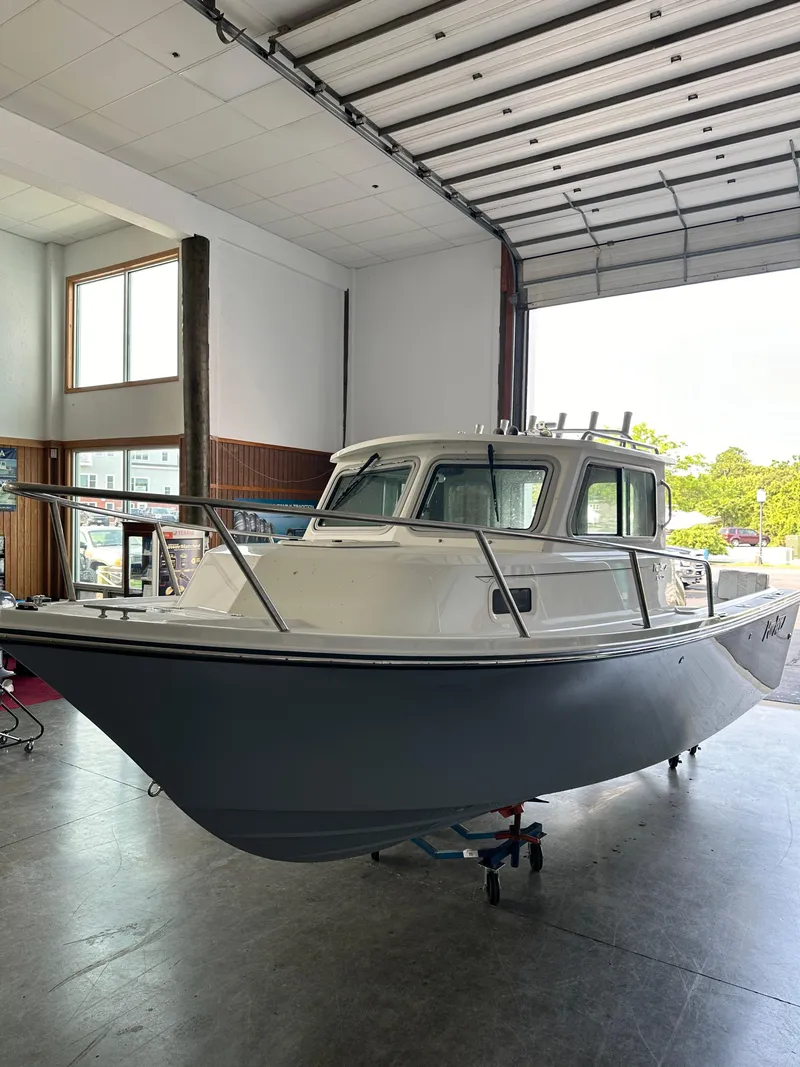 Slide: The Image of 2025 Parker 2120 Sport Cabin boat displayed in a spacious indoor showroom. - 2