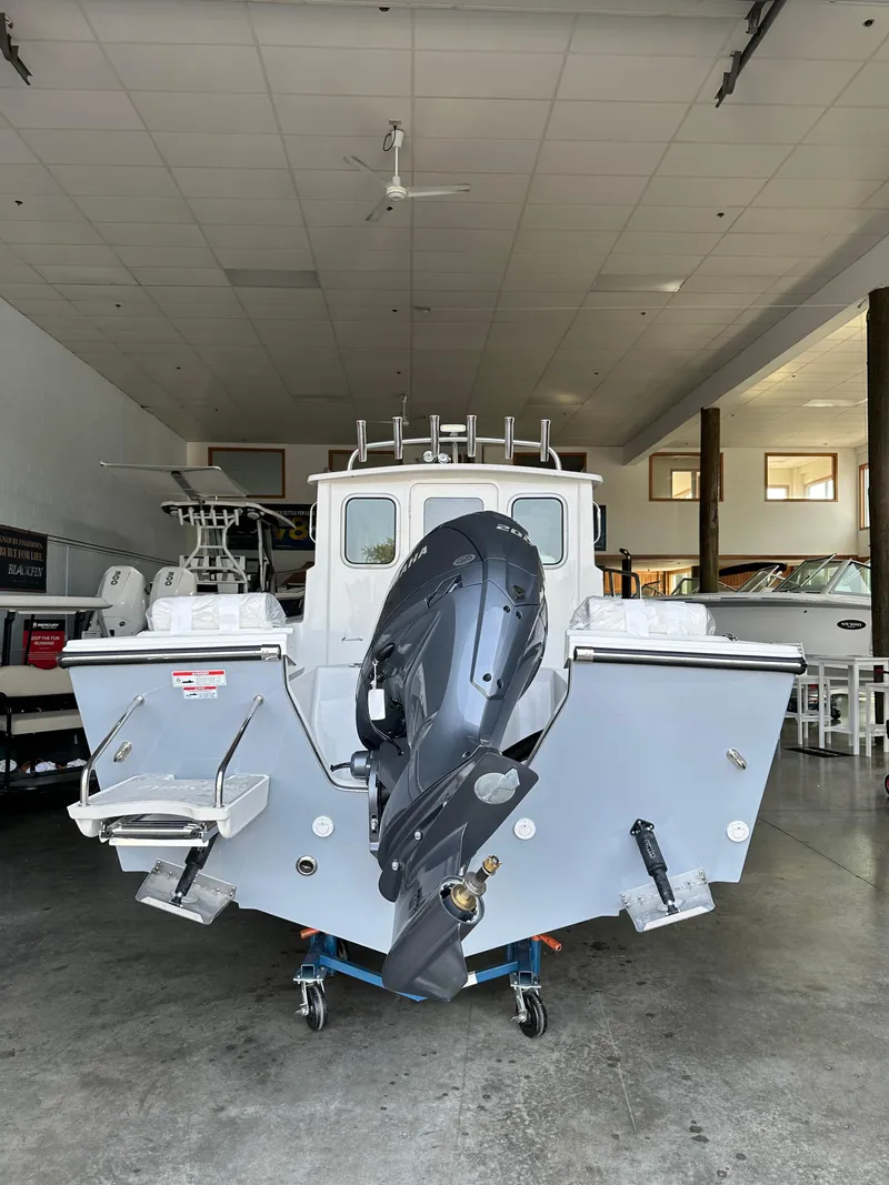 Slide: The Image of 2025 Parker 2120 Sport Cabin boat in a showroom, rear view with outboard motor. - 4