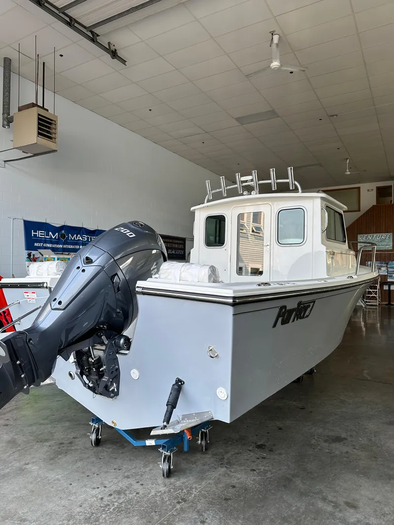 Slide: The Image of 2025 Parker 2120 Sport Cabin boat in showroom, featuring outboard motor and sleek design. - 5
