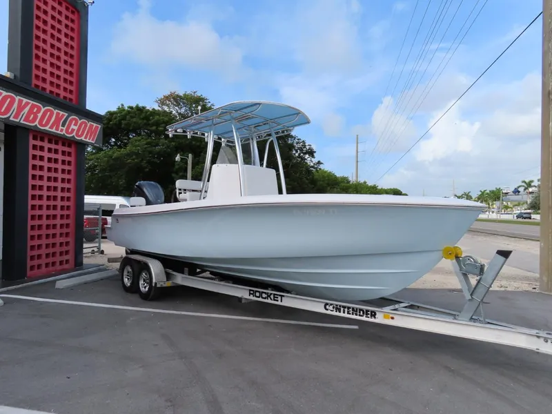 Slide: The Image of 2024 Contender 24S boat on trailer, parked outdoors under blue sky. - 2