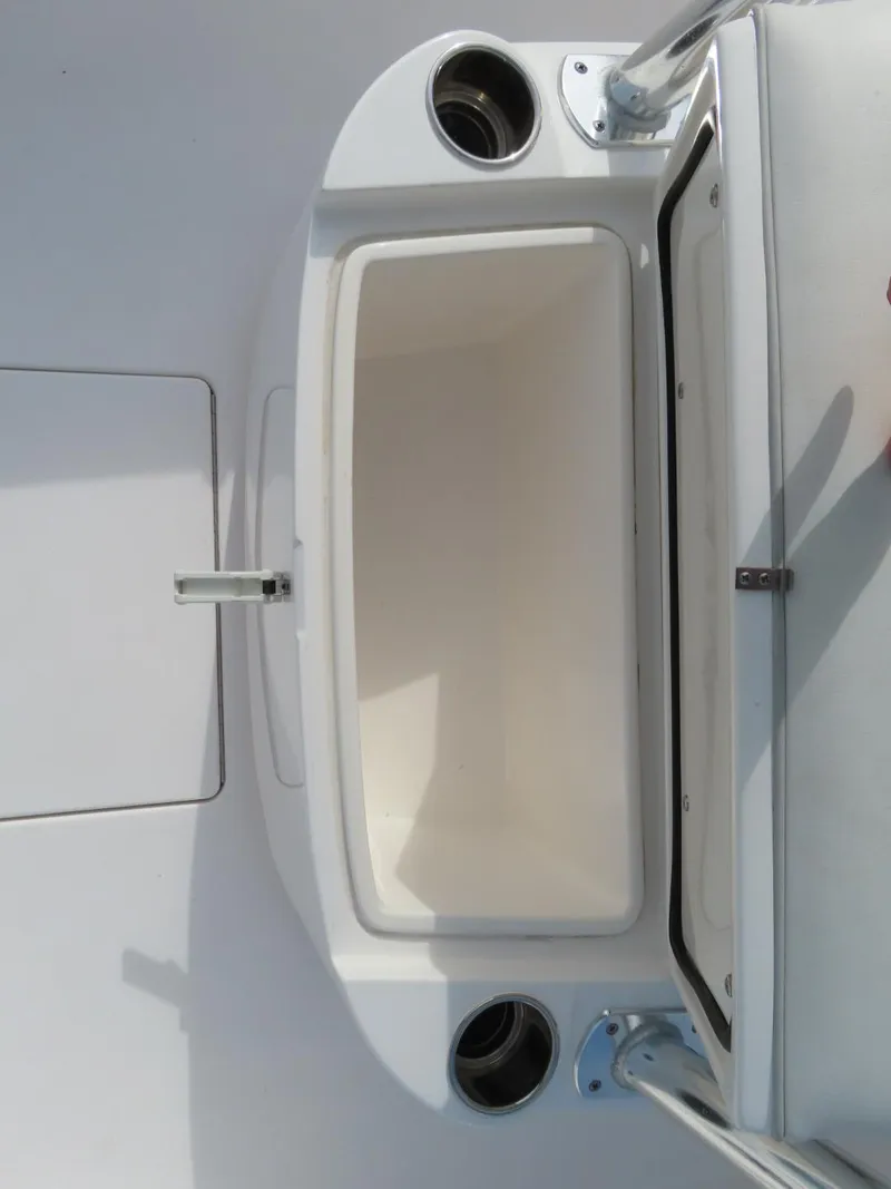 Slide: The Image of 2024 Contender 24S boat storage compartment with open lid and cup holders. - 20