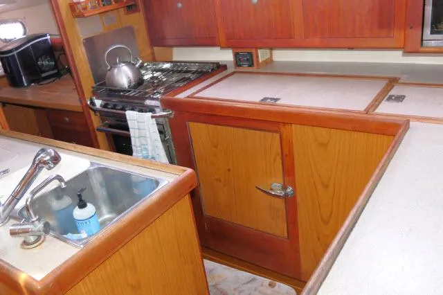 Slide: The Image of Galley kitchen in 2000 Hunter 460 sailboat with wooden cabinetry and stainless steel sink. - 12