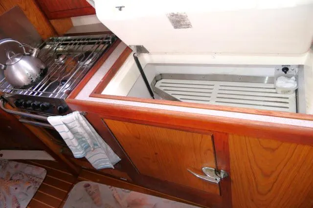 Slide: The Image of Wooden yacht kitchen with stove, kettle, and open storage compartment. Hunter 460, 2000 model. - 13