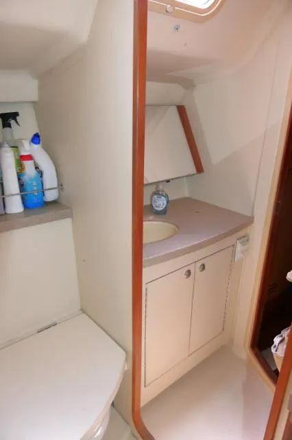 Slide: The Image of 2000 Hunter 460 yacht bathroom with sink, cabinet, and cleaning supplies. - 30
