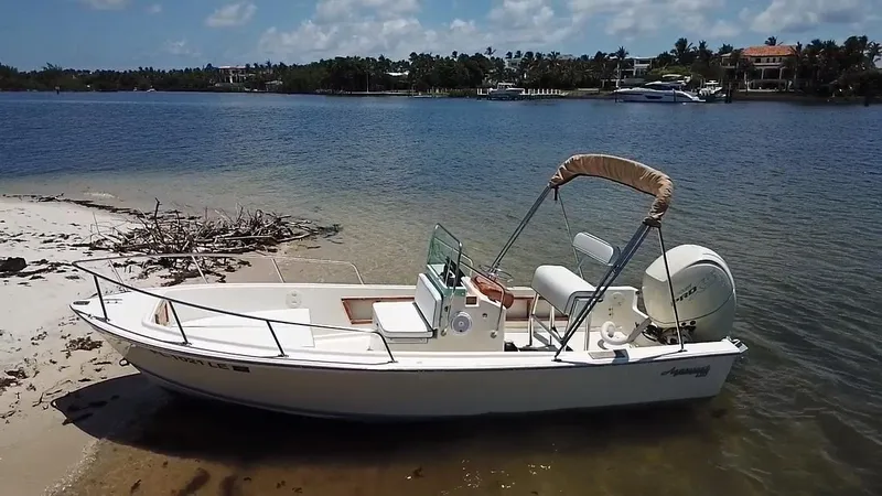 Slide: The Image of 1984 Aquasport 17 CC boat on sandy shore with calm water and clear sky. - 5