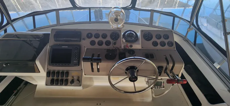 Slide: The Image of 1996 Carver 400 Cockpit Motor Yacht helm with steering wheel and control panel. - 10