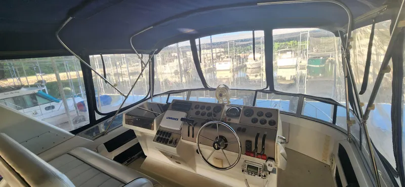 Slide: The Image of Interior view of 1996 Carver 400 Cockpit Motor Yacht helm with marina backdrop. - 8