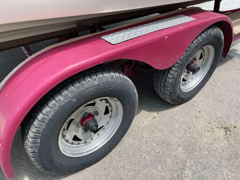 Slide: The Image of Close-up of a 1998 Rinker 212 Captiva Cuddy trailer wheels on pavement. - 19