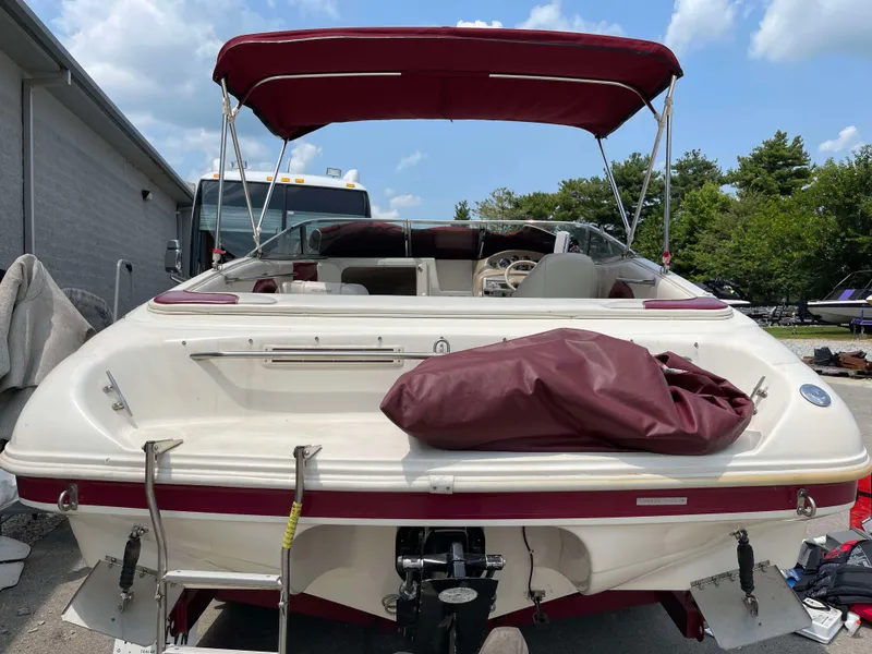 Slide: The Image of 1998 Rinker 212 Captiva Cuddy boat with maroon canopy and ladder, parked outdoors. - 2