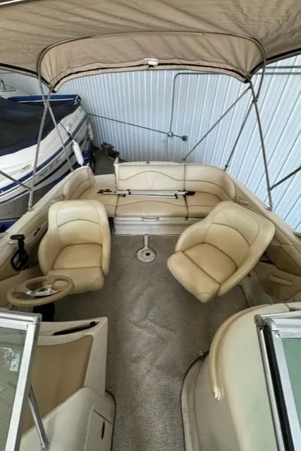 Slide: The Image of 2000 Sea Ray 210 Bow Rider with beige interior and canopy in storage. - 13