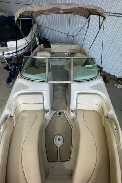 Slide: The Image of 2000 Sea Ray 210 Bow Rider boat with beige interior and canopy in storage. - 7