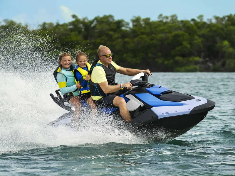 Slide: The Image of Family enjoying a ride on 2024 Sea-Doo Spark 3up jet ski in open water. - 7
