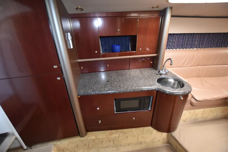 Slide: The Image of 2004 Formula 400 Super Sport yacht interior with kitchenette, featuring wood cabinets and a compact sink. - 16
