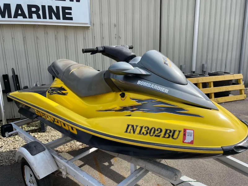 The Image of Yellow 2002 Sea-Doo RX jet ski on trailer, parked outside a marine shop. - 0